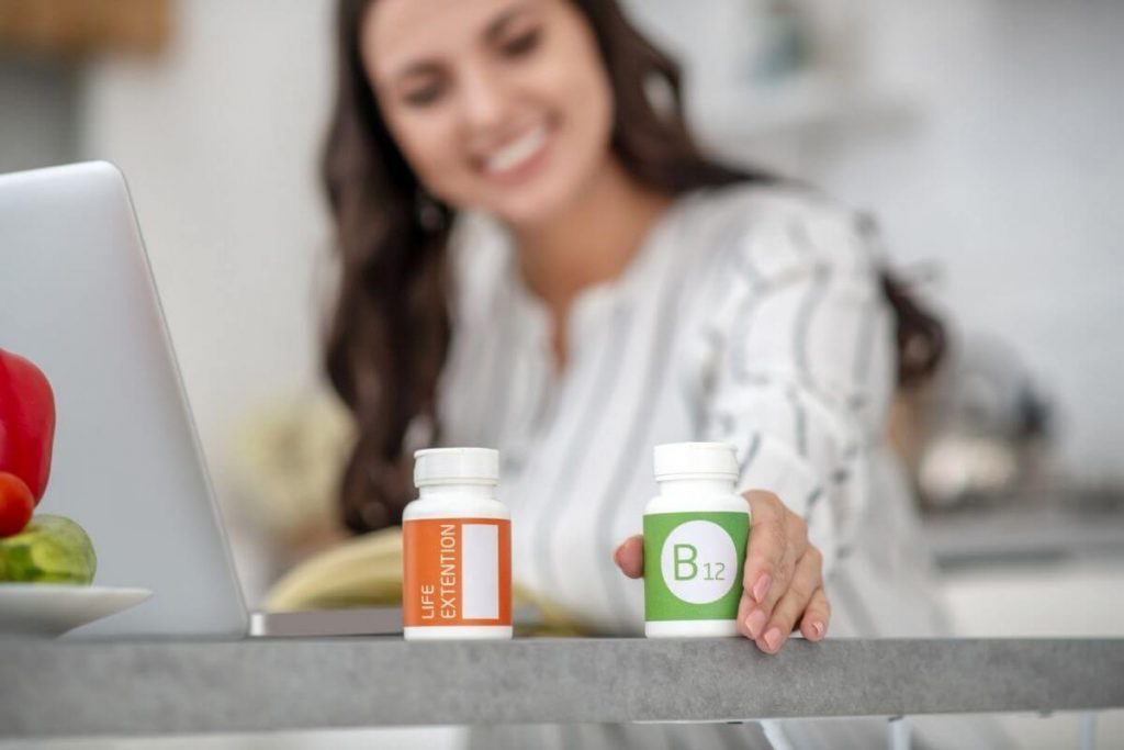 A young woman with a bottle of vitamin B12