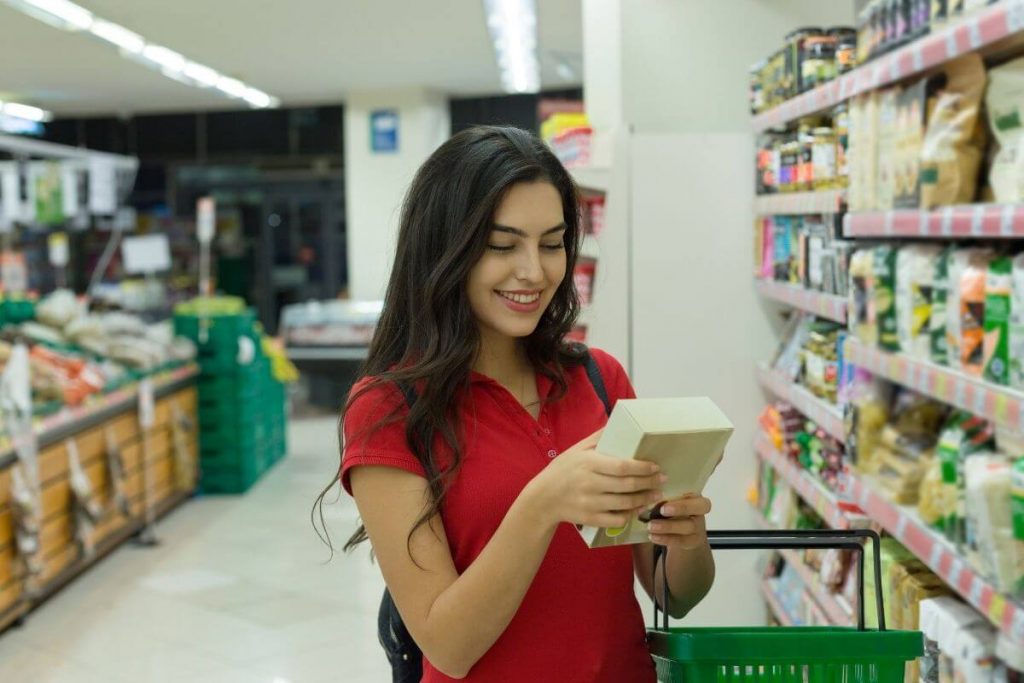 Young woman with long black hair smiling and reading the label on the back of a box