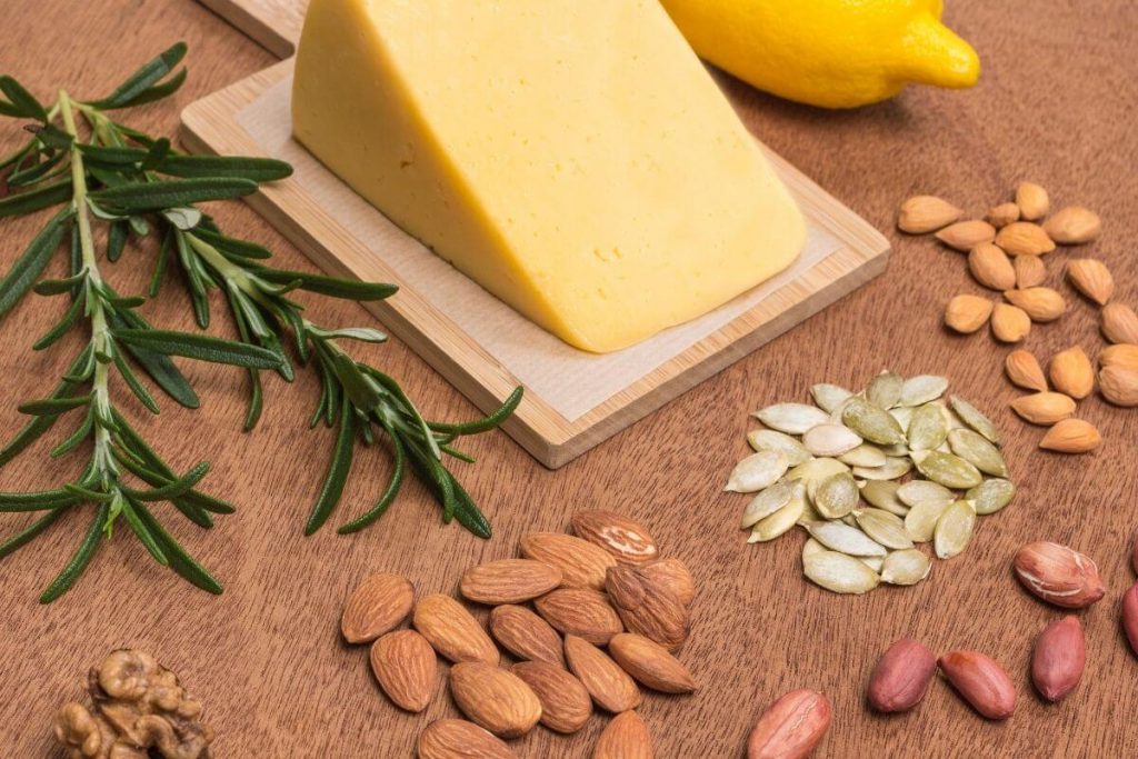 A block of vegan cheese surrounded by a variety of nuts - photo by Oleanaa from Getty Images