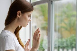 Woman looking out the window - photo by SHOTPRIME from Canva
