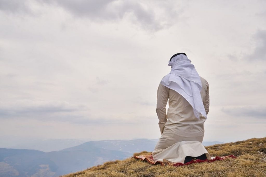 Man praying on top of a mountain