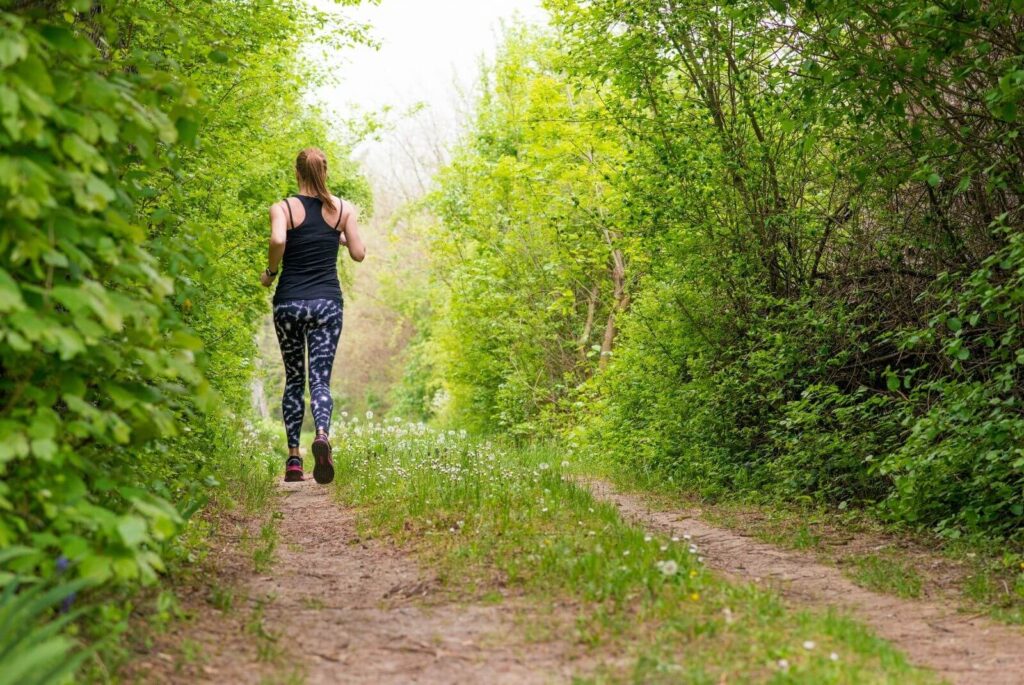 A woman running along a track in a green forest