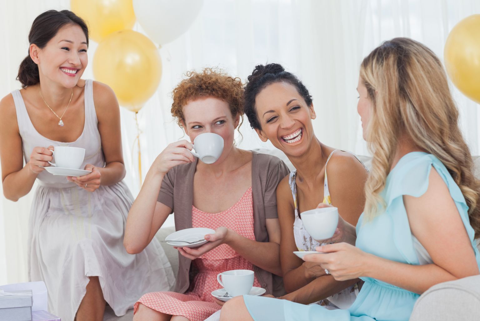 Women friends drinking tea and laughing at a party