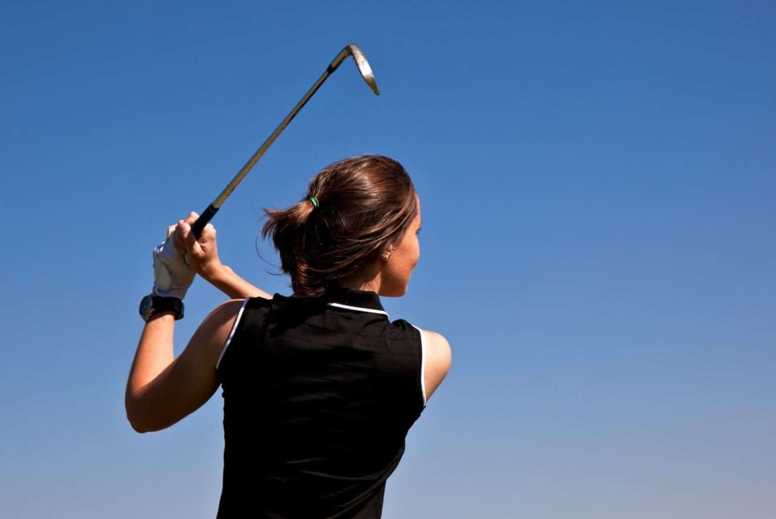 Young woman swinging a golf club Fitzer - Getty Images