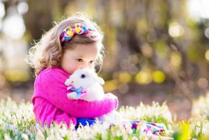 Little girl with scared, white, Easter bunny in a field of flowers - FamVeld from Getty Images