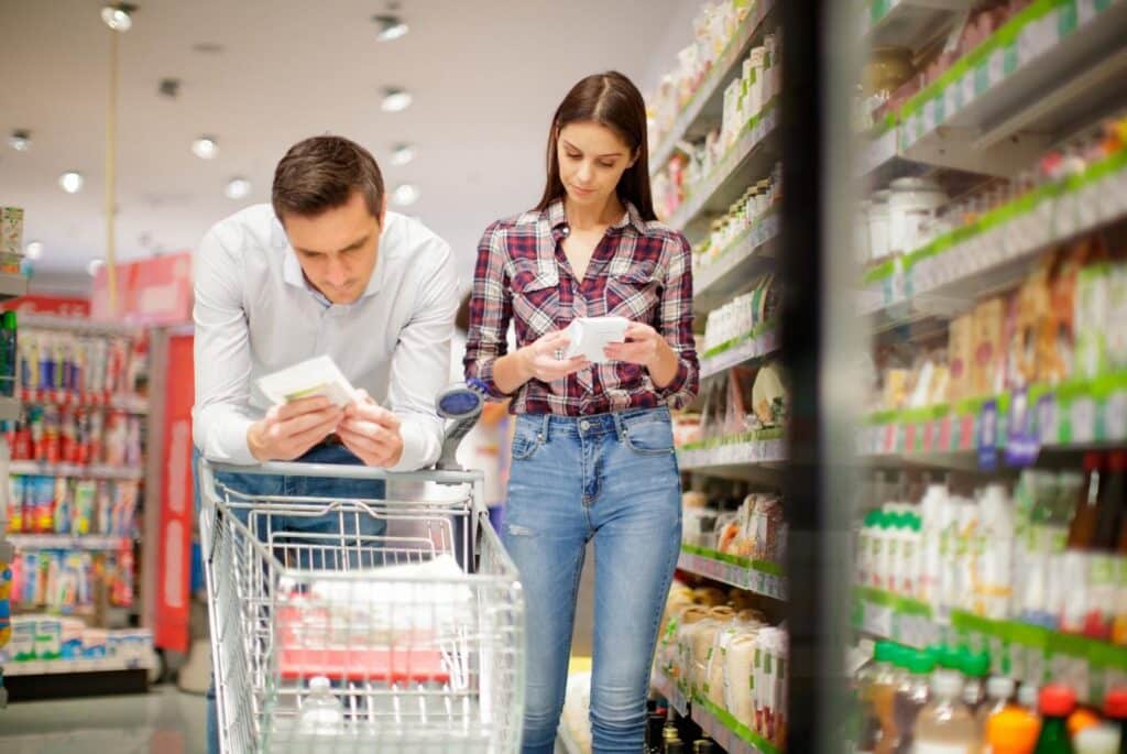 Young couple reading labels on food packages - zoranm - Getty Images Signature